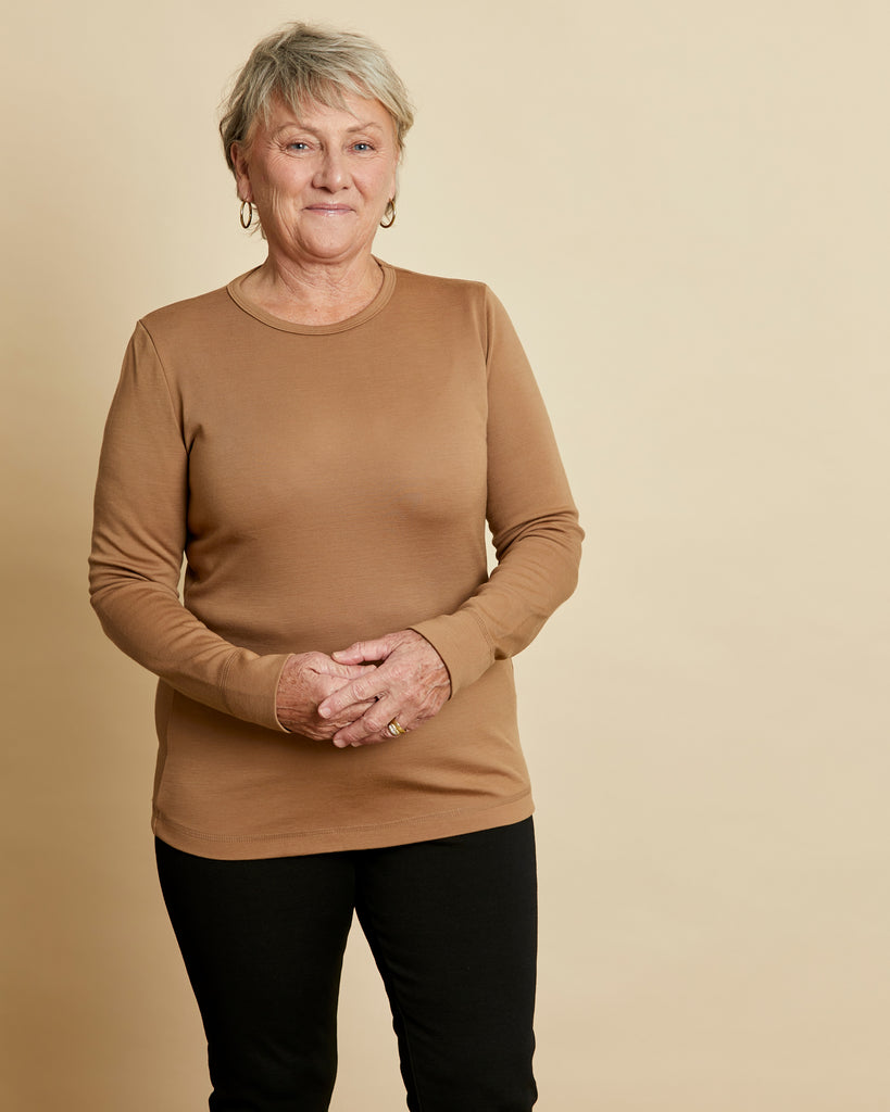 Woman wearing soft Australian Merino wool long sleeve crew neck in camel. Designed to wear next to the skin either as a base layer or as a t.shirt style on its own. This style is perfect for layering. Made in Australia at Woolerina's workrooms at Forbes in central west NSW.