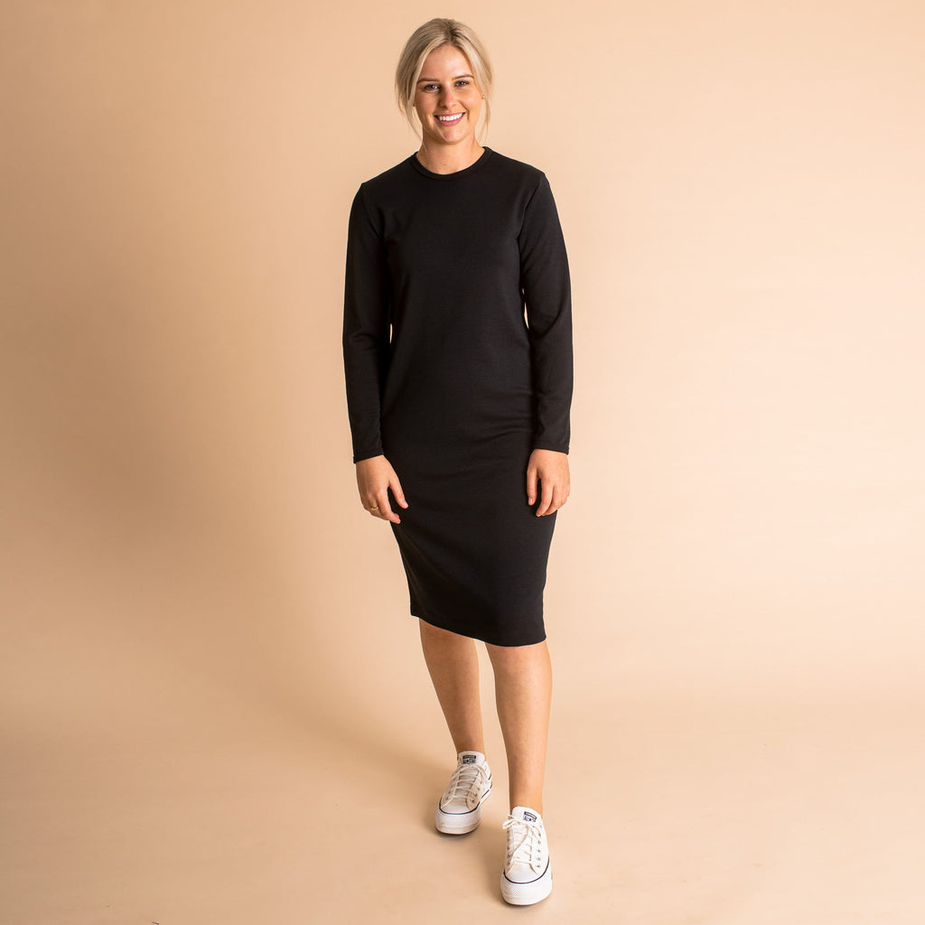 Woman wearing soft Australian Merino wool relaxed fitting long sleeve crew neck dress in black. Designed as a relaxed fit and sitting around knee length. This style is perfect as a base to add other layers. Made in Australia at Woolerina's workrooms at Forbes in central west NSW.